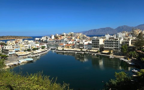 Blick auf die weiß getünchten Gebäude rund um einen ruhigen Hafen in Agios Nikolaos