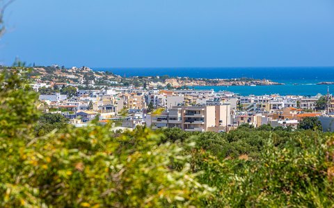 Die weißen Gebäude von Heraklion erstrecken sich bis zum blauen Meer, mit grünen Sträuchern