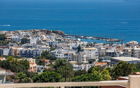 Weiße Stadt und Hafen von Chersonissos am tiefblauen Meer aus der Luft