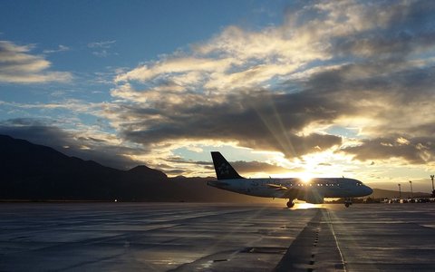 Verkehrsflugzeug auf dem Vorfeld des Flughafens Dubrovnik bei Sonnenuntergang, dahinter Hügel als Silhouetten