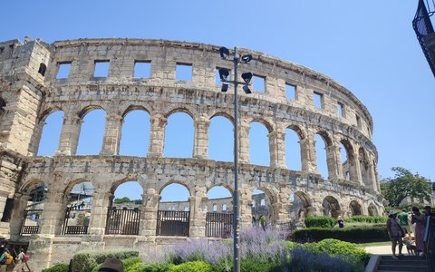 Die Steinmauern mit ihren Bögen am römischen Amphitheater in Pula unter klarem Sommerhimmel