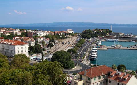 Luftaufnahme des Hafens und der Kais von Split mit liegenden Schiffen, der Stadt ringsum sowie dem Meer und den Inseln dahinter