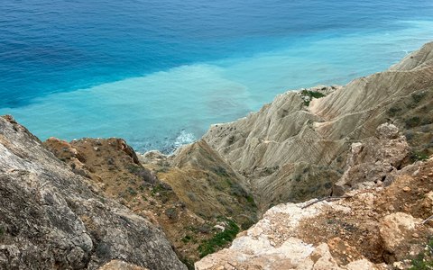 Blick auf helle Felsklippen, die in ein leuchtend türkisfarbenes Meer abfallen
