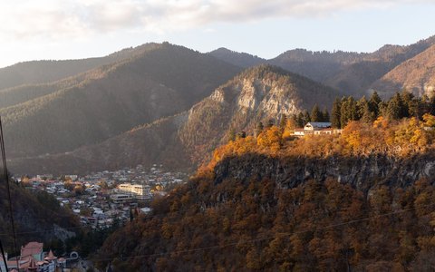 Bewaldetes Bergtal in Herbstfarben mit einer Stadt im Talgrund im warmen Sonnenlicht