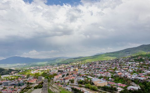Blick von oben auf Gori und grüne Hügel unter weißen Wolken