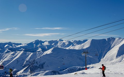 Schneebedeckte Kaukasusgipfel über den Skipisten von Gudauri unter tiefblauem Himmel