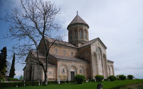 Große steinerne orthodoxe Kirche mit Kuppelturm neben einem kahlen Baum in Telawi unter blassem Himmel