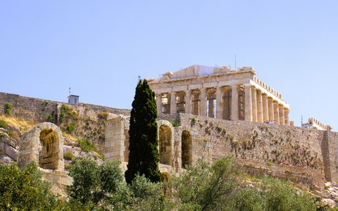 Der Parthenon auf dem Felsen der Akropolis über Bäumen und alten Mauern