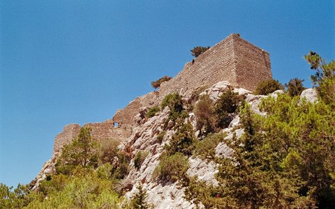 Steinmauern der Burg Monolithos auf einem felsigen Vorsprung unter blauem Himmel