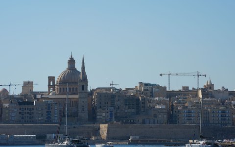 Blick auf die Boote im Hafen vor den Kuppeln und Kirchtürmen von Valletta unter klarem blauem Himmel