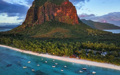 Luftaufnahme des Berges Le Morne Brabant über Palmen, einem weißen Strand und einer türkisfarbenen Lagune