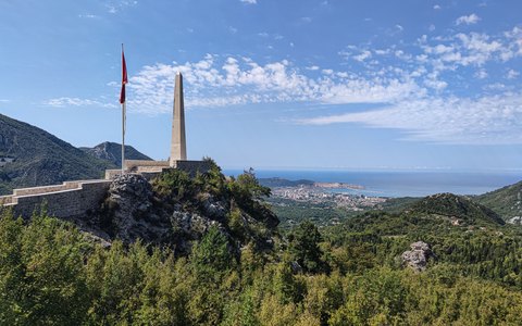 Blick auf grüne Hügel, die zum Meer abfallen, mit der Stadt Bar an der Bucht