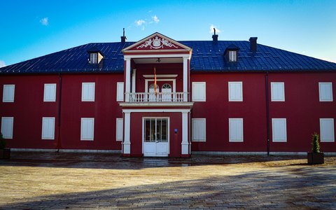 Ein roter zweistöckiger Palast mit weißen Fenstern und einem Balkon