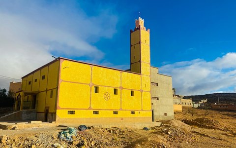 Leuchtend gelbe Moschee mit quadratischem Minarett in Taroudant unter blauem Himmel mit weißen Wolken