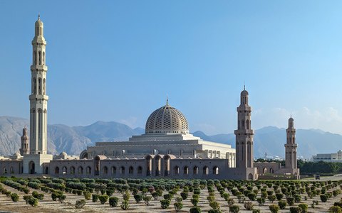 Vor einem klaren blauen Himmel die Kuppeln und hohen Minarette der Sultan-Qabus-Moschee
