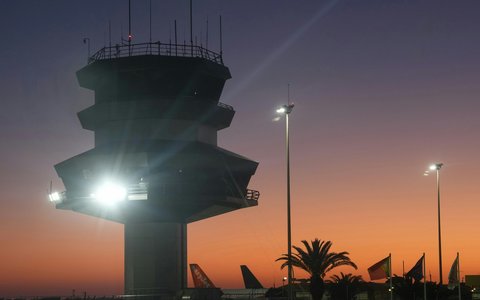 Silhouette des Kontrollturms am Flughafen Faro vor orangefarbenem Abendhimmel