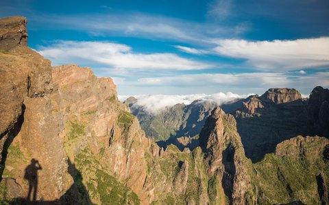 Zerklüftete Vulkangipfel und Grate, gesehen vom Pico do Arieiro, mit Wolken darunter und blauem Himmel
