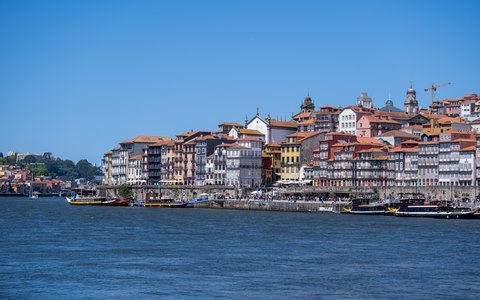 Die bunten Häuser des Viertels Ribeira in Porto erheben sich über dem Fluss Douro unter blauem Himmel