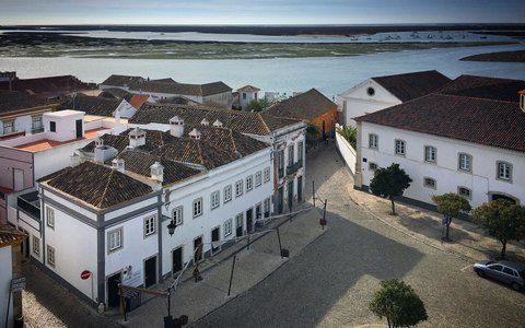 Alte weiße und gekachelte Gebäude von Tavira am Fluss unter klarem blauem Himmel