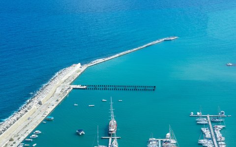 Lange Hafenmauer und vertäute Boote im klaren türkisfarbenen Wasser von Castellammare del Golfo aus der Luft