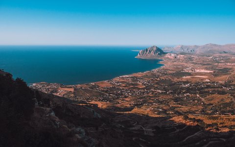Blick von oben auf Küstenebene und Bucht von San Vito Lo Capo, dahinter Landzunge und blaues Meer