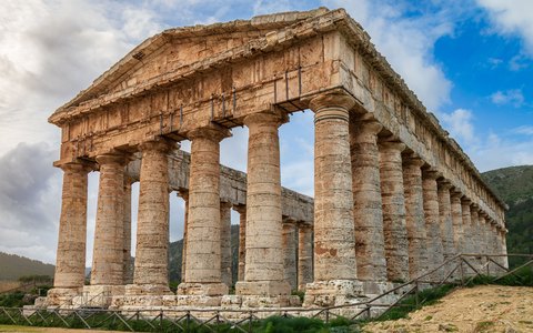 Dorischer Tempel von Segesta auf einem grünen Hang unter blauem Himmel mit weißen Wolken