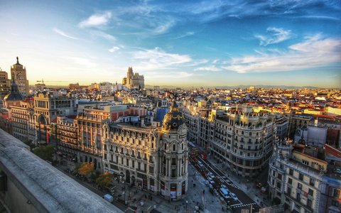 Blick von einem Dach über Madrids Gran Vía und das Metrópolis-Gebäude mit Kuppel unter blauem Himmel