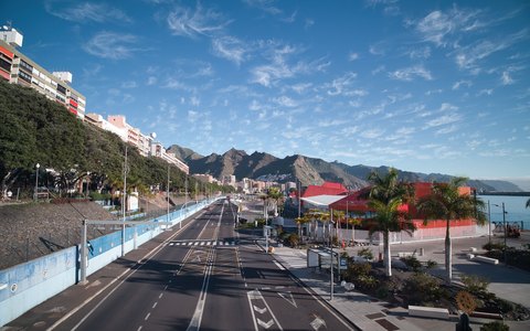 Uferstraße in Santa Cruz de Tenerife mit bunten Gebäuden, dahinter Berge und blauer Himmel