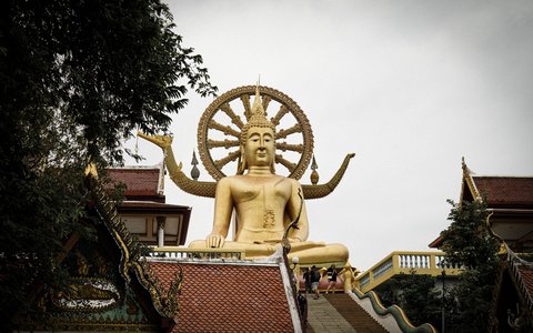 Goldene Statue des sitzenden Großen Buddha über Tempeldächern auf Koh Samui