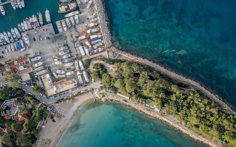 Luftaufnahme des Yachthafens von Kemer mit Booten, einer grünen Halbinsel und türkisfarbenem Meer