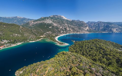 Luftbild der türkisfarbenen Blauen Lagune und des Strands von Ölüdeniz vor bewaldeten Hügeln und Bergen