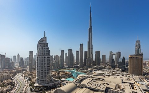Luftaufnahme von Downtown Dubai unter klarem blauem Himmel, der Burj Khalifa ragt über die Türme hinaus
