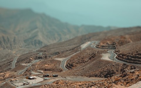 Luftbild einer Straße, die sich die kahlen felsigen Hänge des Dschabal Dschais hinaufwindet